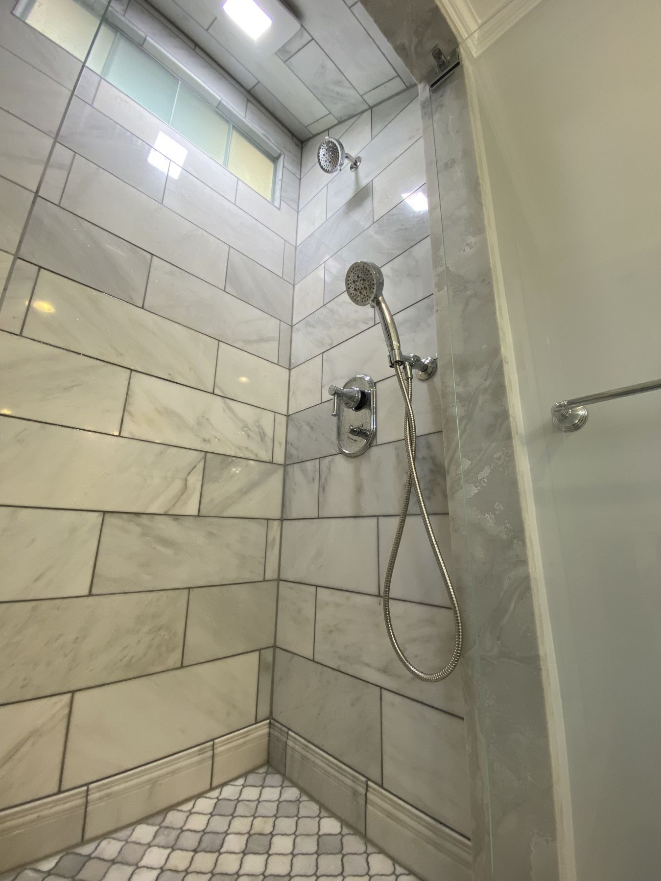 Marble walk-in shower with a mosaic floor