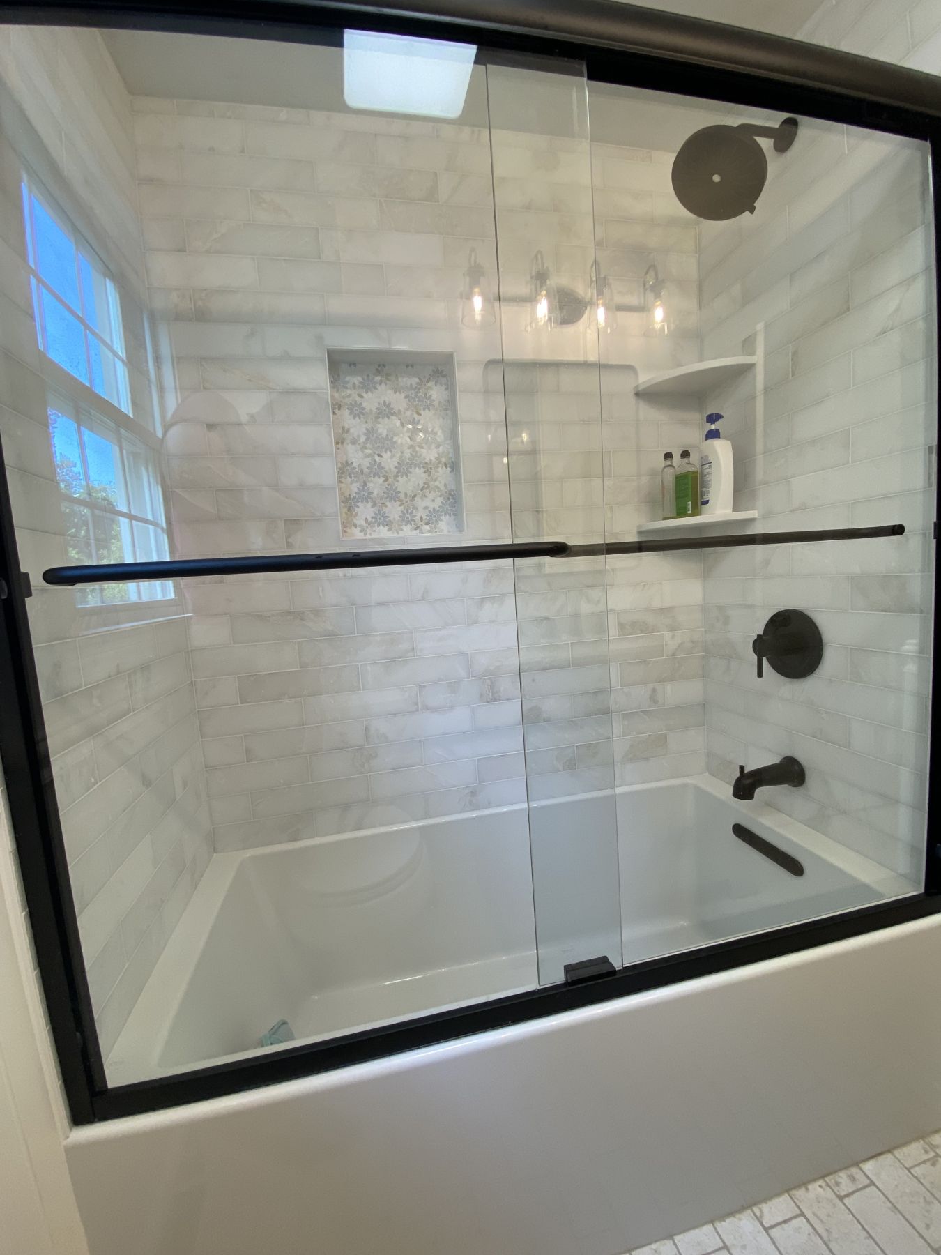 Tub and shower surround tiled in marble with a glass enclosure