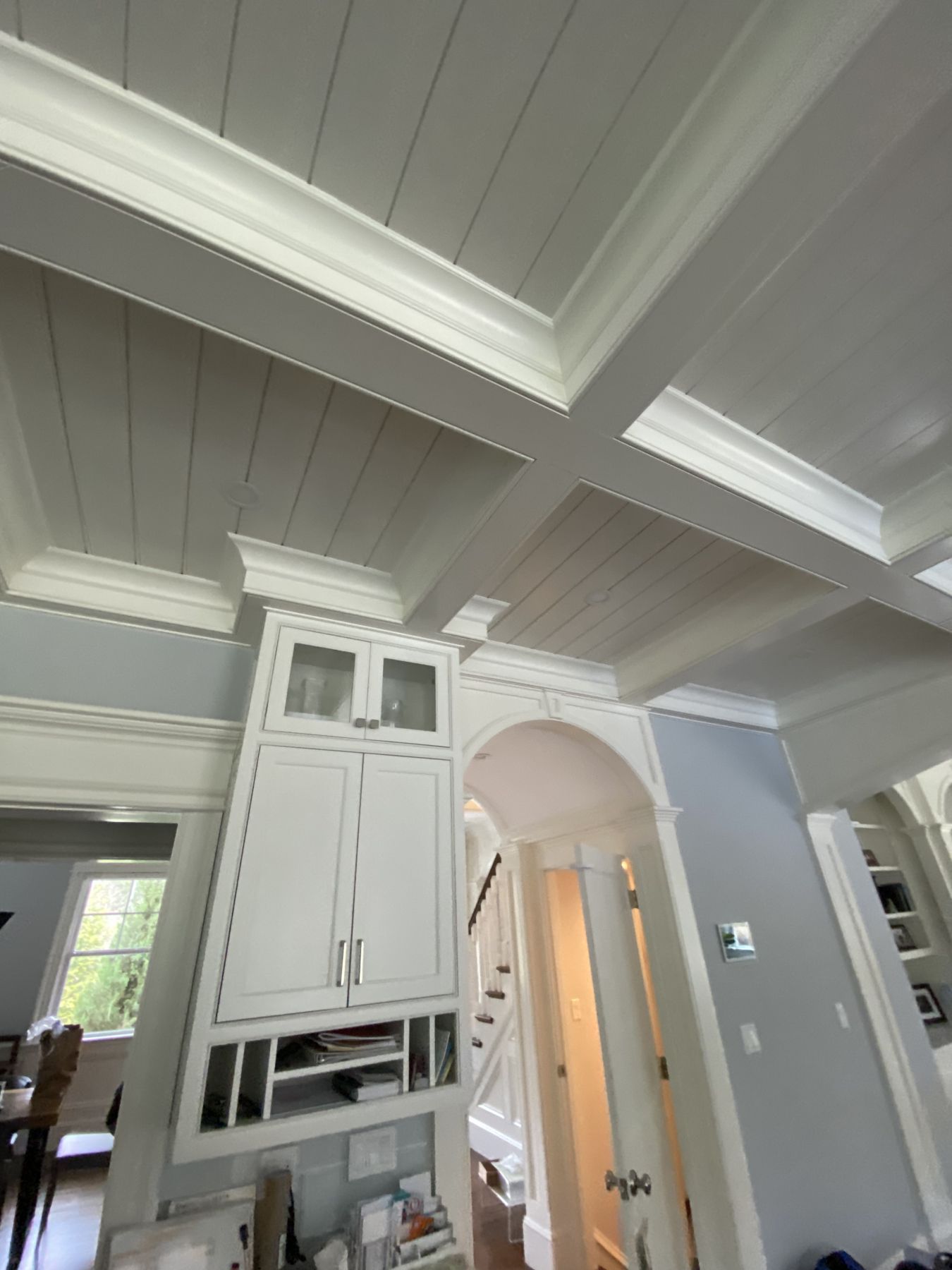 Custom built-in cabinetry with glass uppers beside an arched opening